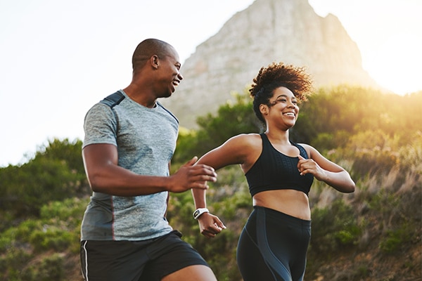 Sports, workout and couple walking by a mountain training for a race, marathon or competition. Fitness, nature and athletes doing an outdoor cardio exercise for health, energy and endurance at sunset