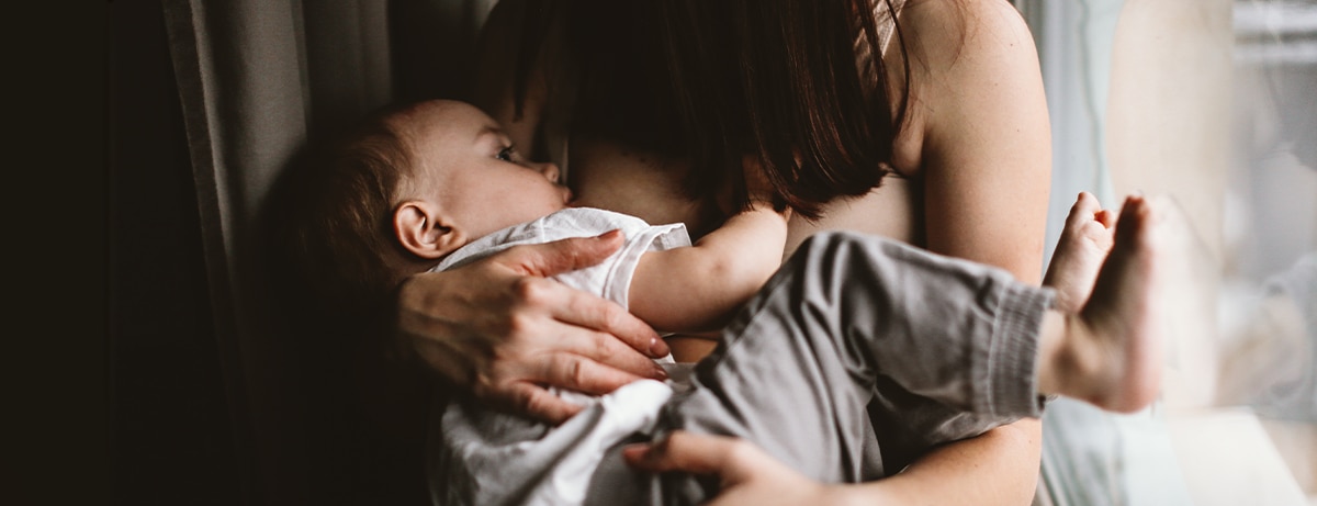 authentic candid woman mom breastfeeds toddler baby, brown toning and lifestyle and dark style, soft focus