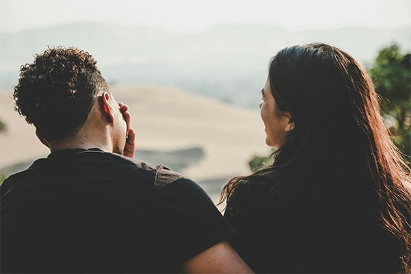 Male and female cuddling looking out on scenic view