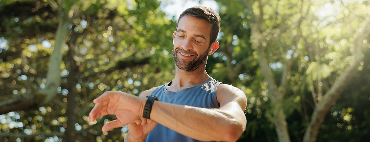 Happy, fitness and man in park with time for exercise, training and workout in morning. Sports, runner and person check smart watch for heart rate and progress for health, wellness and performance