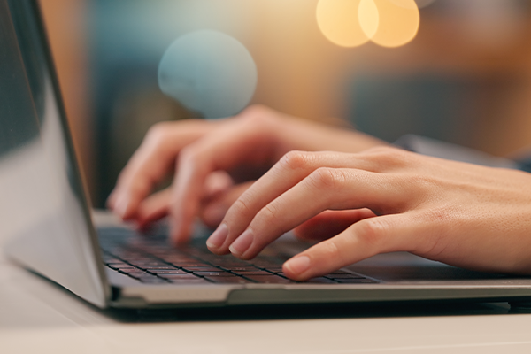 Person, hands and typing on laptop in office for email, spreadsheet and proposal or application for work. Woman, online and technology with bokeh for task or drafting, writing notes and report.