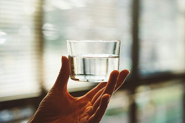 Hand holding glass of water with blurred background