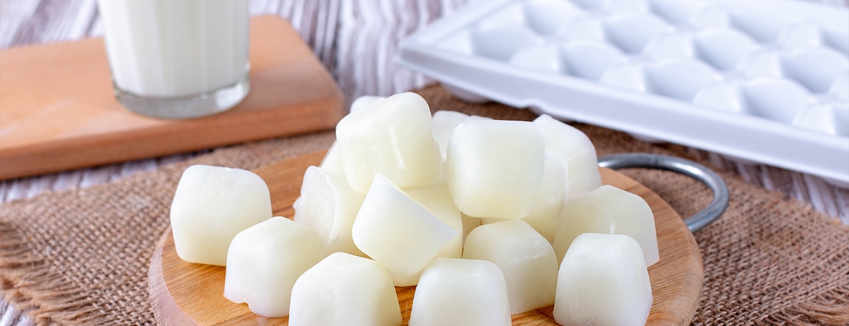 Milk ice cubes on a cutting board a white wooden table