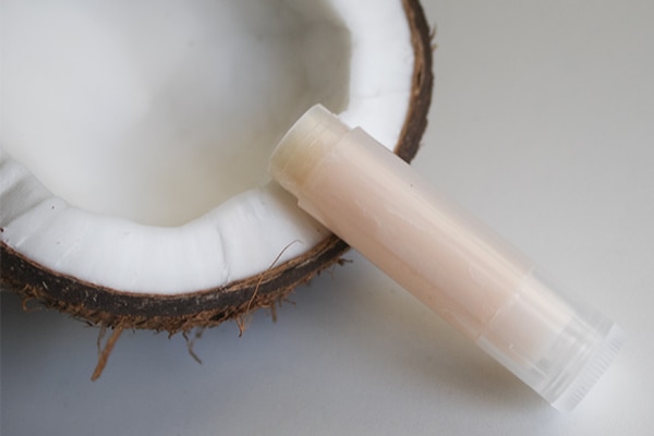 Hygienic lipstick isolated on a white background with coconut cracked in two halves. Layout with coconut oil hygiene for winter care.
