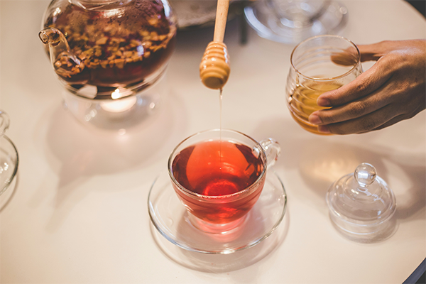 Manuka honey pouring into tea