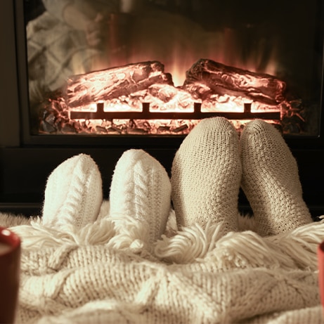 Couple in knitted socks near fireplace at home, closeup