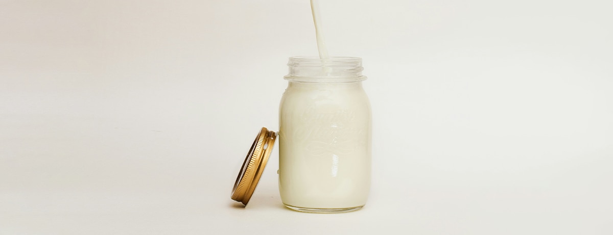 Glass jar of milk on a white background