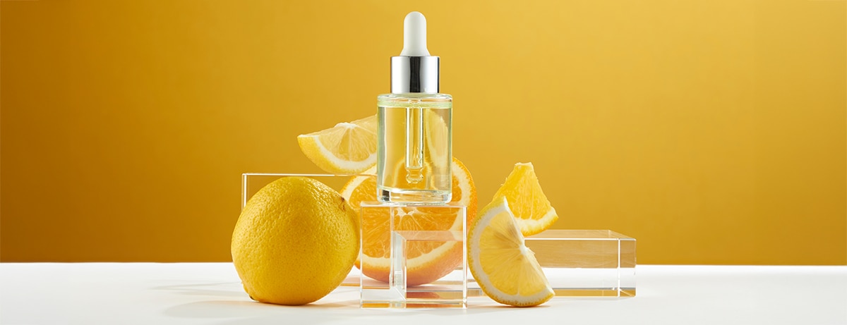 A front view of lemon decorated with cosmetic jar and transparent podium in orange background