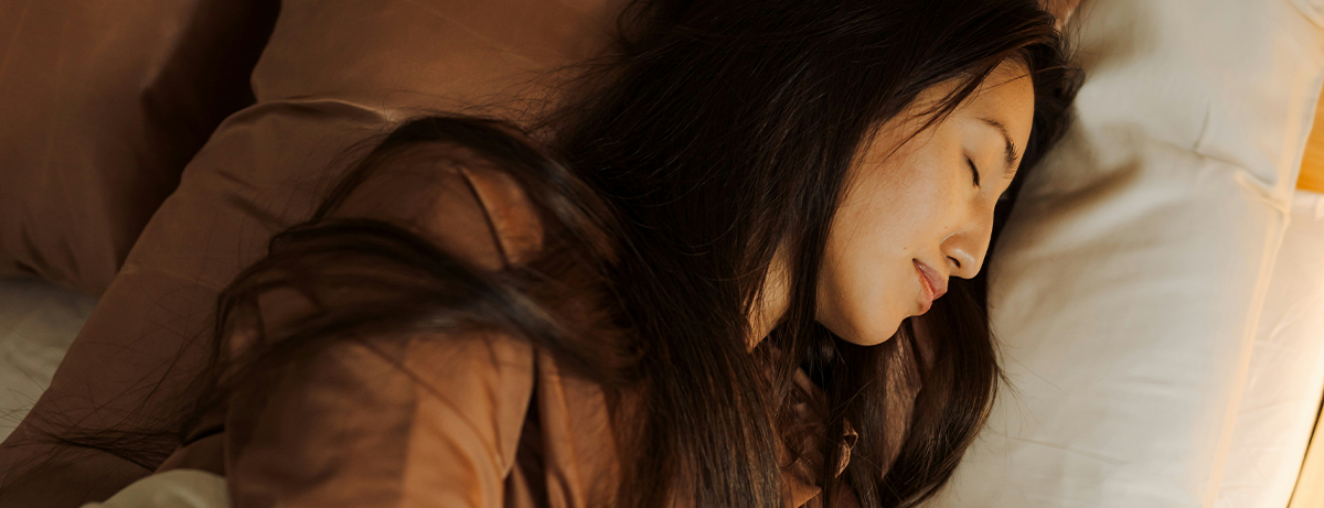 Asian female asleep on bed with calm expression