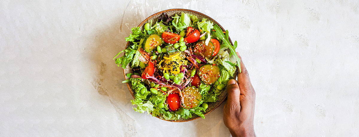 Salad in bowl with hand holding
