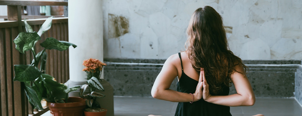 Female sitting in yoga pose in bedroom