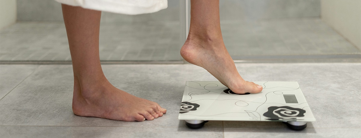 Feet close up stepping onto weighing scales