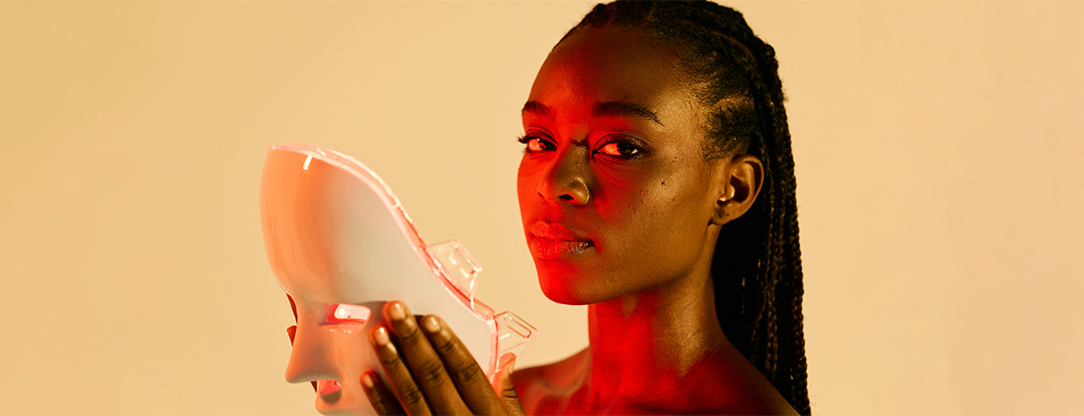 Female looking at camera holding light therapy mask