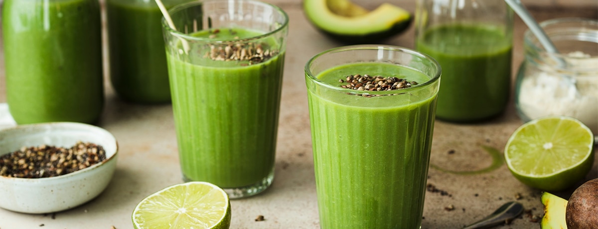 Two glasses of green superfood smoothies in kitchen setting