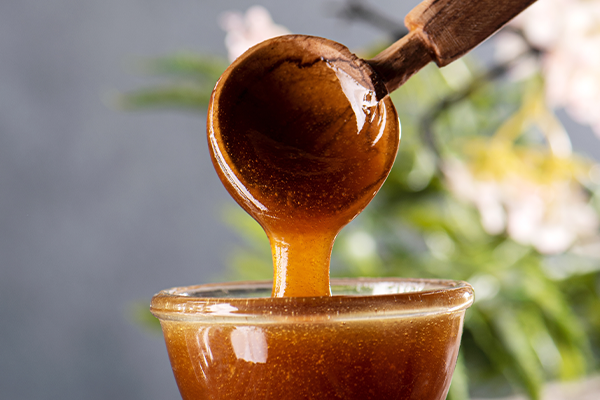 Manuka honey flowing from wooden spoon