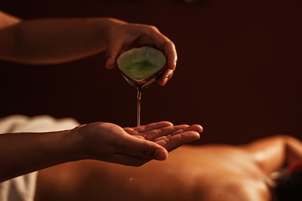 Masseur pouring aroma oil on hand, for massage on back of customer. Relaxation young male customer get service aromatherapy massage with masseuse in spa salon. Aromatherapy massage, Selective focus.