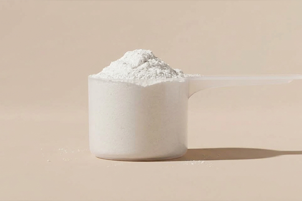 Creatine in a scoop on a beige background