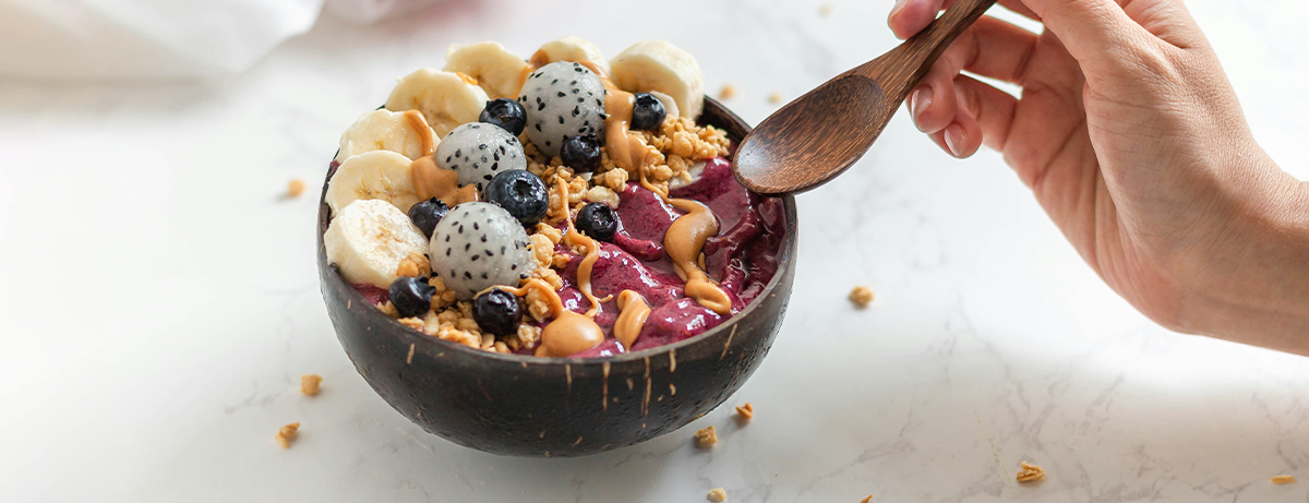 Hand holding a spoon over a bowl of berries and nuts