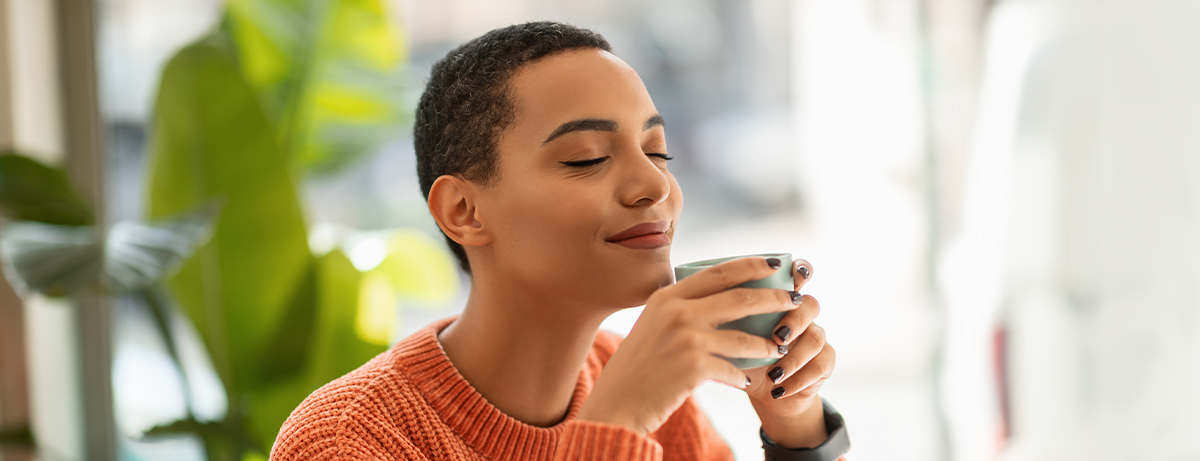 Glad calm pretty young latin woman enjoy peace and spare time, drink cup of coffee, warm moment in modern cafe, office interior. Rest, relax, ad and offer, human emotions, lifestyle