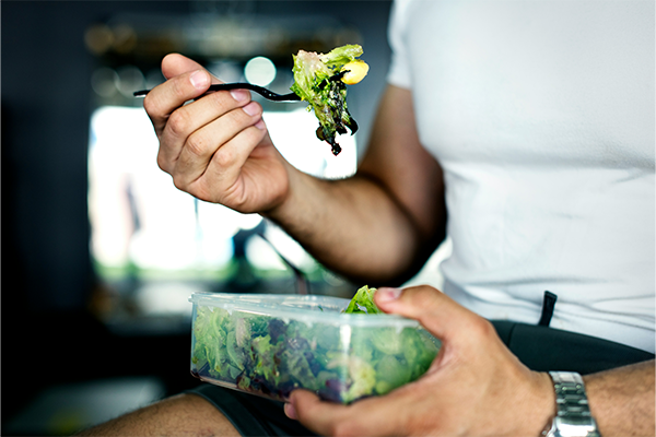 Male close up eating a salad from a tub