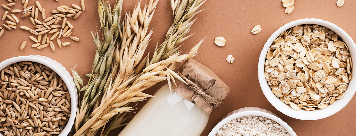 Oat products from flakes, milk, flour and whole grains top view. Healthy food, vegetarian diet concept.
