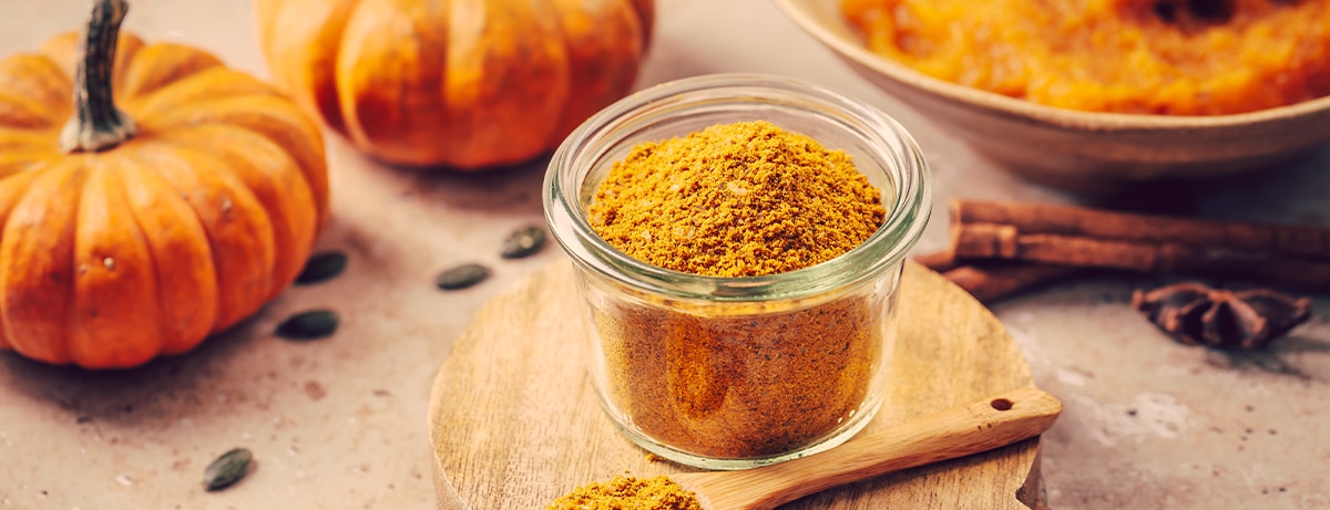 Pumpkin and selection of spices on a brown wooden background