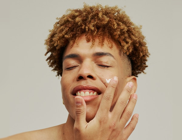 portrait man fashion model wellness skincare male studio healthy lotion isolated latino posing moisturiser white background