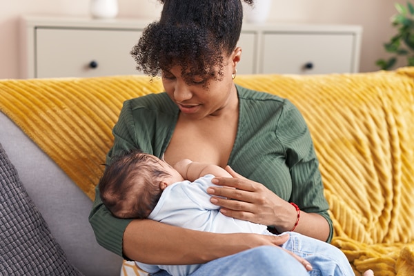 Mother and son sitting on sofa breastfeeding at home