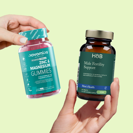 hands holding 2x male fertility supplements on green background