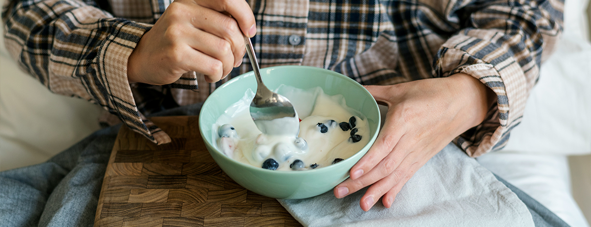 Female holding a bowl of yoghurt in green bowl
