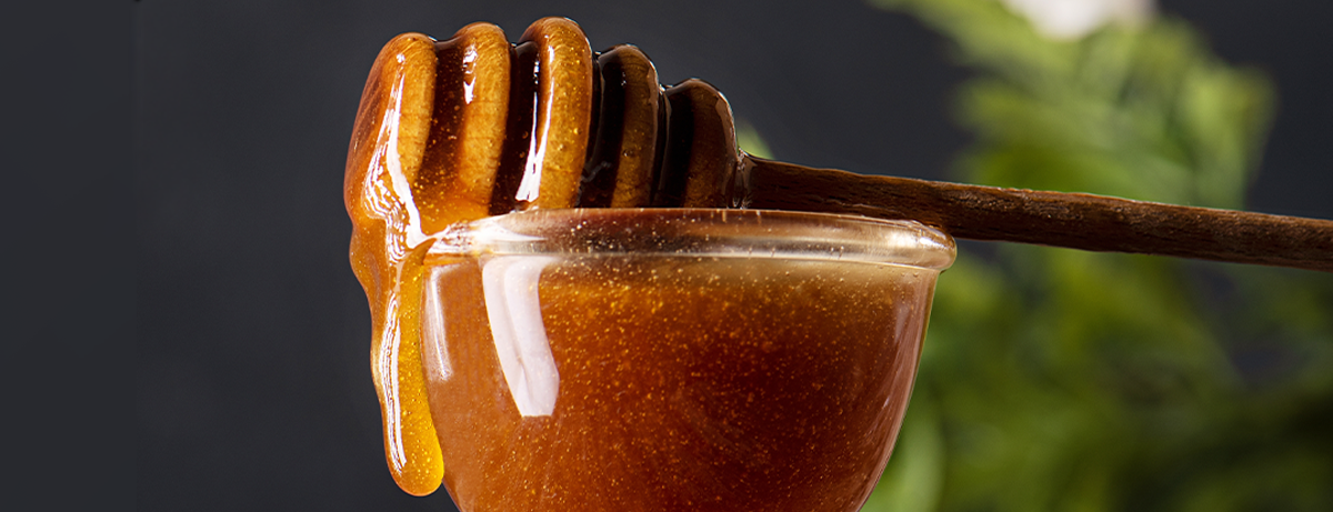 New zealand manuka honey dripping from wooden dipper