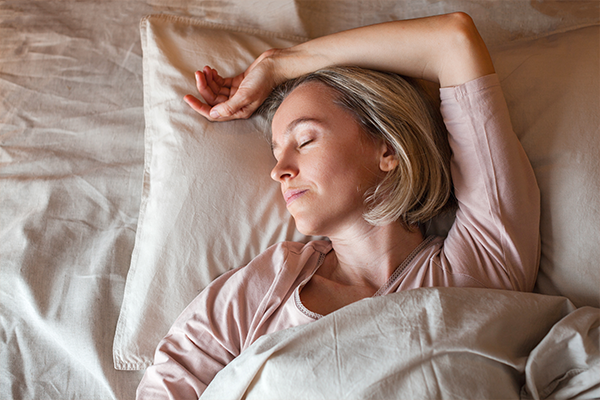 Pretty middle aged woman sleeping on bed in modern apartment. Female in bedroom at home