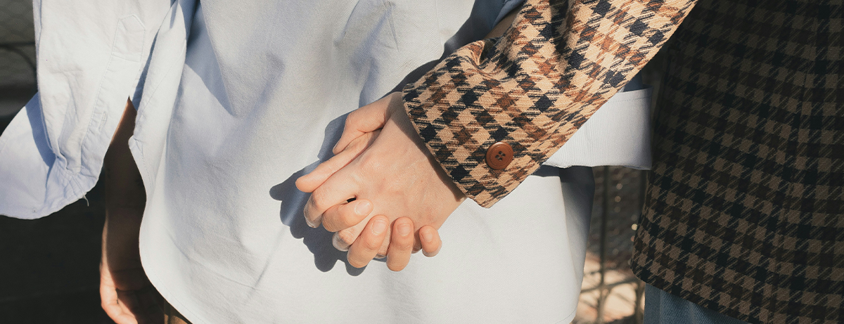 Close up of male and female holding hands from behind