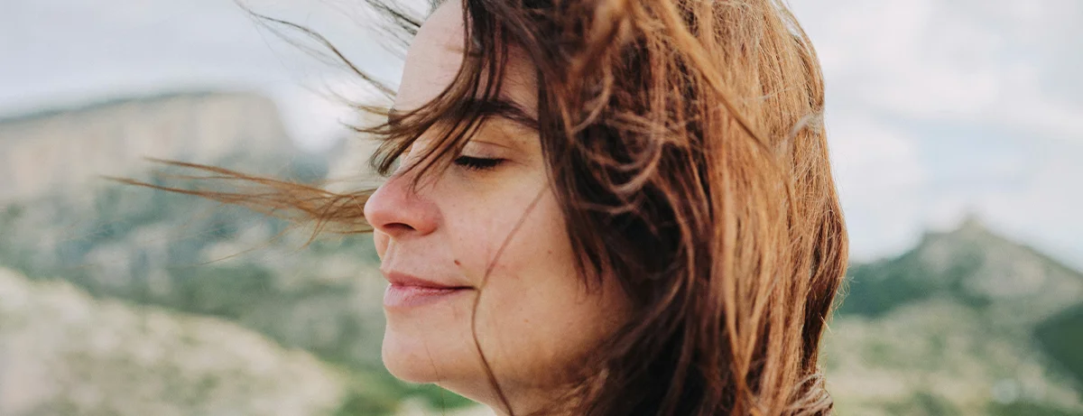 Female standing outdoors, close up with wind blowing