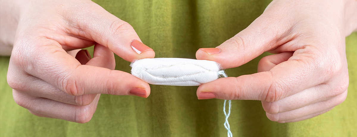 Close up of tampon being held by female in green dress