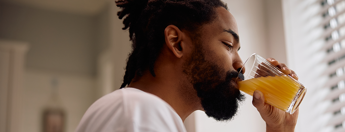Male standing at the window drinking some juice