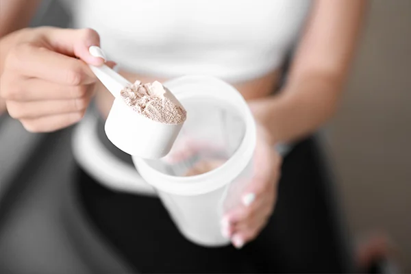 Sporty young woman with protein at home, closeup