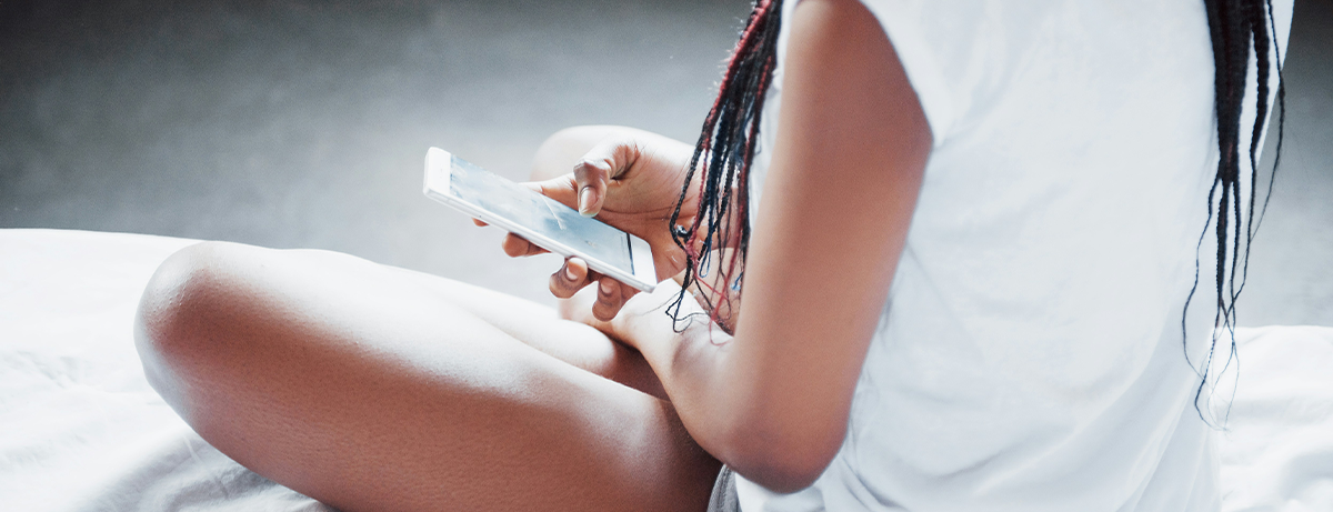 Female sitting on the bed with a mobile phone