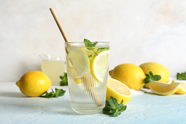 Glass of fresh lemonade with mint and fruits on light blue table