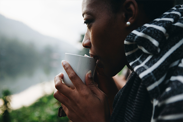 Female on balcony drinking a warm cup of drink