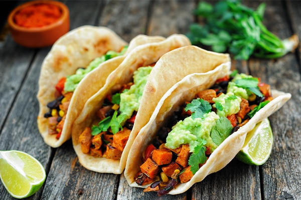 Homemade vegan tacos with black beans, sweet potato and guacamole and tortillas flatbread. Clean eating, plant based food concept