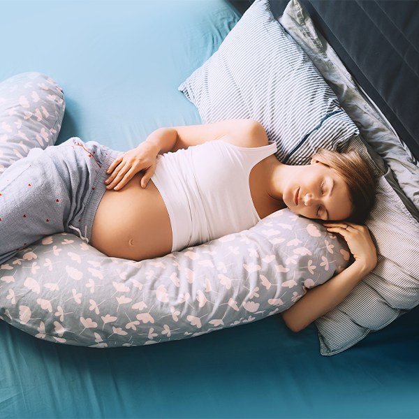 Pregnant female laying on bed in pyjamas asleep