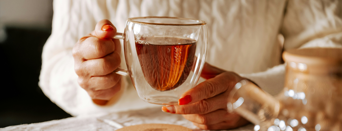 hands holding glass cup of coffee