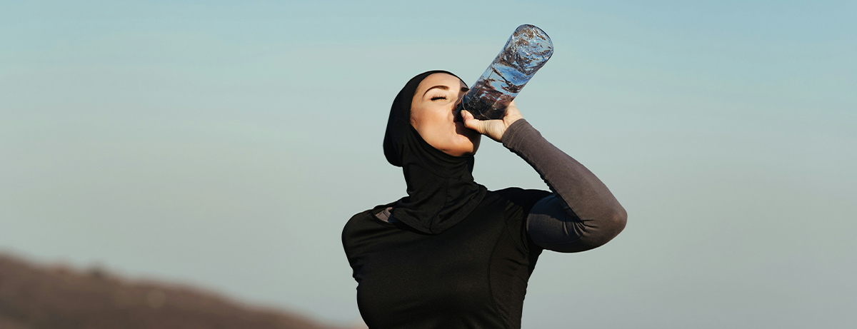 Female in running wear drinking a bottle of water.