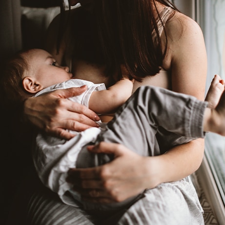 authentic candid woman mom breastfeeds toddler baby, brown toning and lifestyle and dark style, soft focus