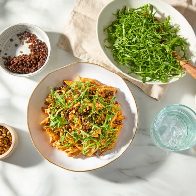 red lentil pasta in a bowl with a mix of greens, grains and on a counter