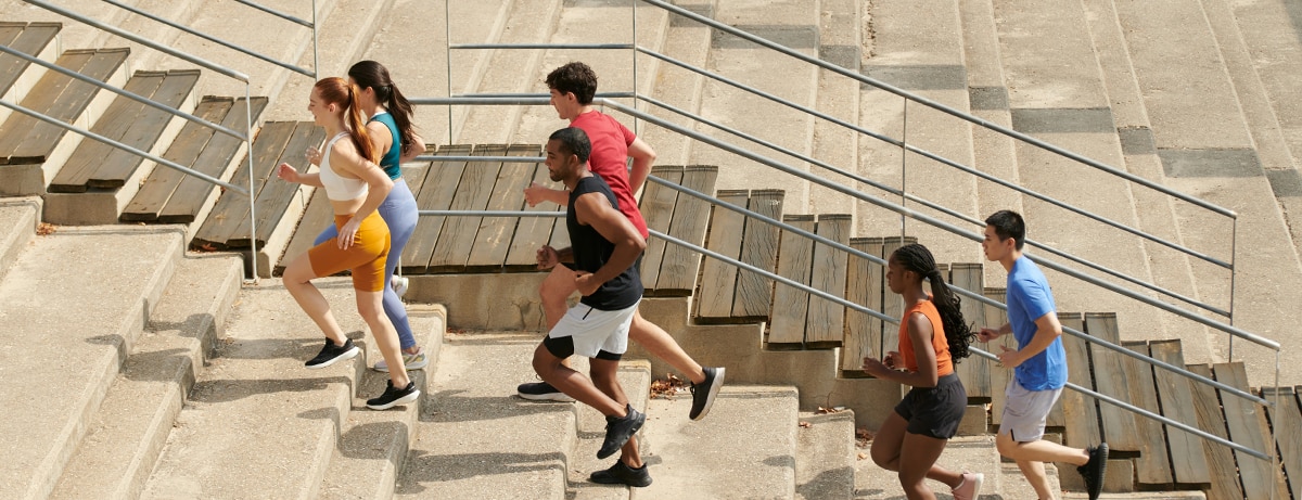 Group of runners running up concrete steps in city location