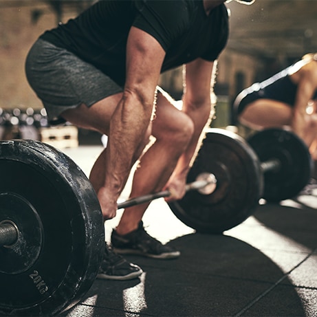 Fit people doing deadlift exercise in gym. Horizontal indoors shot