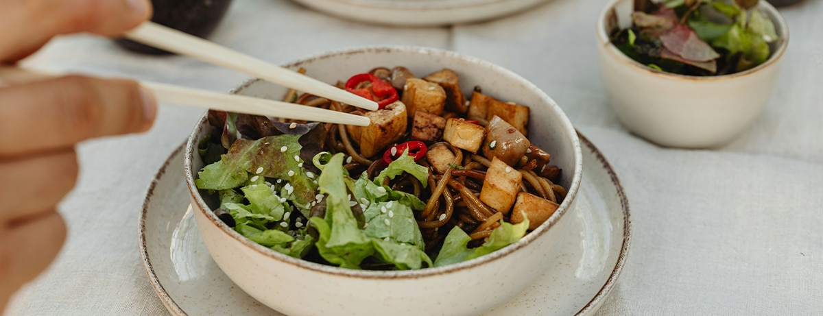 Portion of tofu bites with a spicy pepper salad. Served in a white bowl