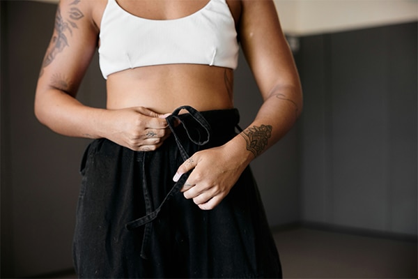 Female standing in front of the camera with hands on stomach